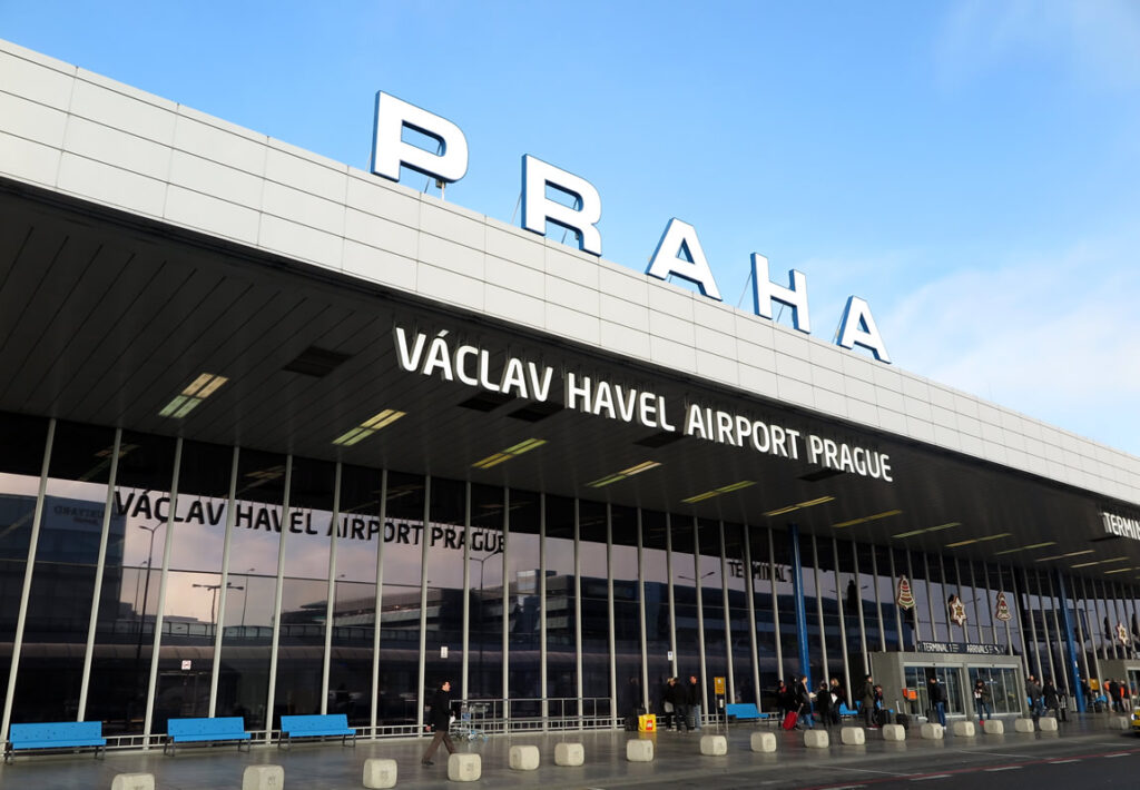 Průčelí budovy letiště s velkým nápisem PRAHA a nápisem Václav Havel Airport Prague