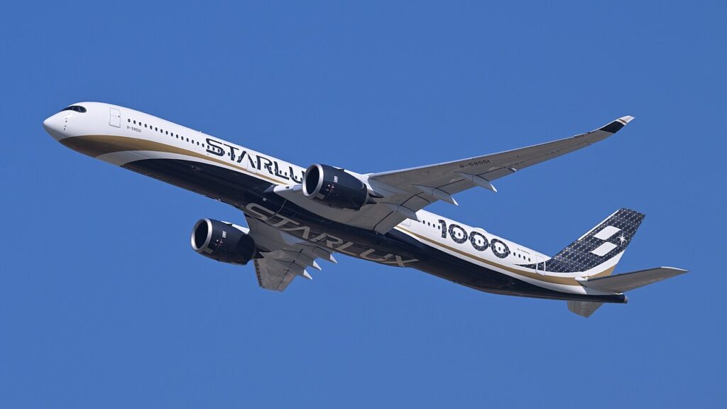 Bílo-černo-zlatý Airbus A350-1000 aerolinky STARLUX stoupá po vzletu na pozadí modré oblohy